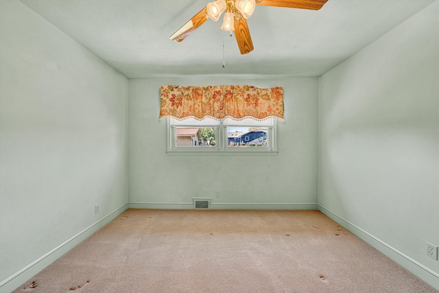 spare room with carpet floors, baseboards, a ceiling fan, and visible vents