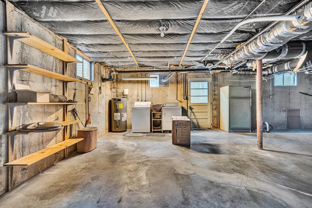 below grade area featuring plenty of natural light, freestanding refrigerator, washing machine and dryer, and electric water heater