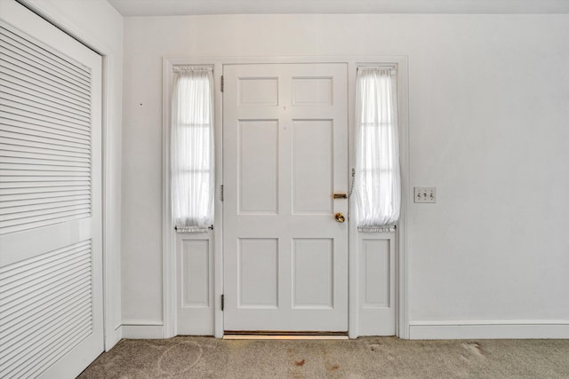 foyer entrance with baseboards and carpet