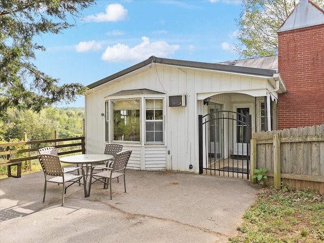 back of house featuring a patio, a gate, outdoor dining space, fence, and board and batten siding