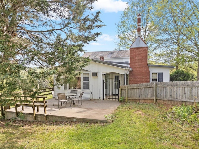back of house with board and batten siding, a patio area, fence, and a lawn