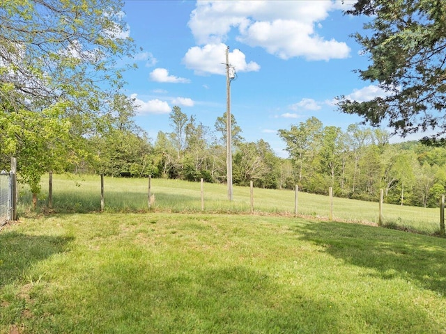 view of yard featuring a wooded view and fence