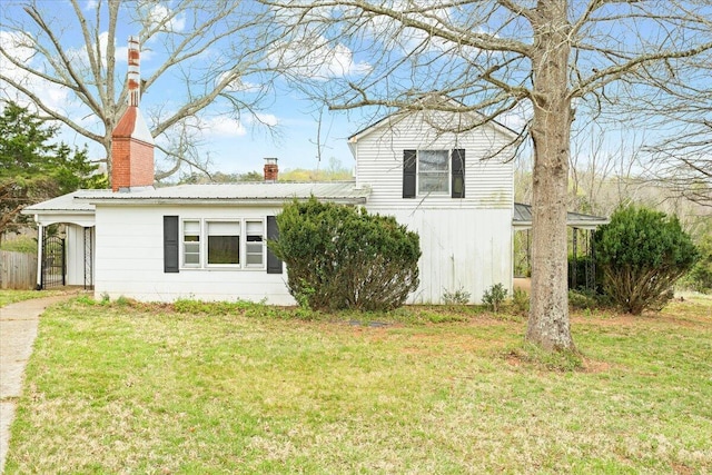 split level home featuring a chimney, a front yard, and metal roof