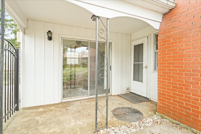 view of exterior entry featuring board and batten siding and brick siding