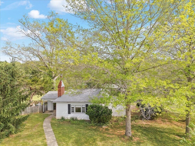 view of front of house featuring a chimney, fence, and a front yard
