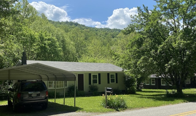 1615 Dolly Ann Dr, Covington, VA 24426 - view of front facade with a front yard, a carport, a wooded view, and a chimney