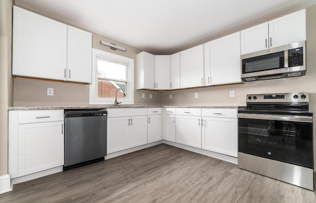 kitchen with white cabinets, wood finished floors, and stainless steel appliances