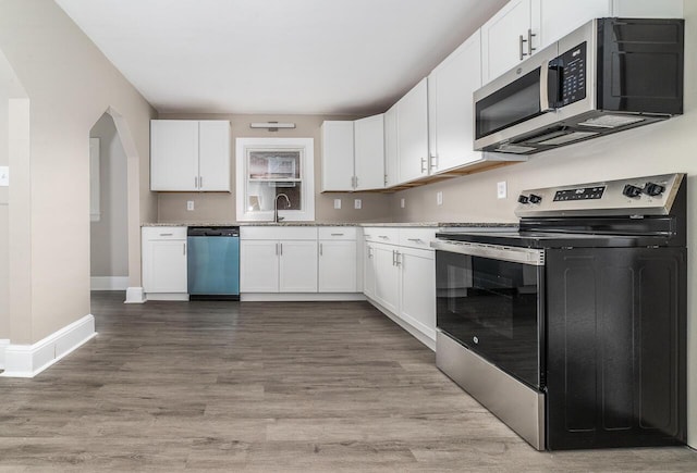 kitchen with white cabinets, a sink, stainless steel appliances, and light stone countertops