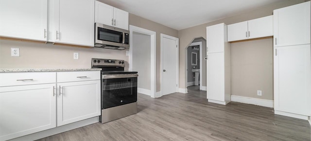 kitchen with white cabinets, stainless steel appliances, light countertops, and light wood-type flooring