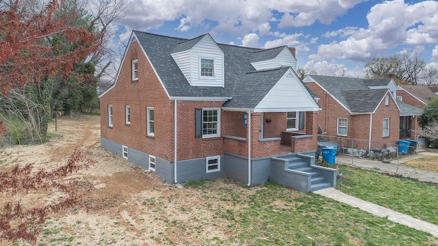 view of front facade featuring brick siding, a shingled roof, fence, and a front lawn