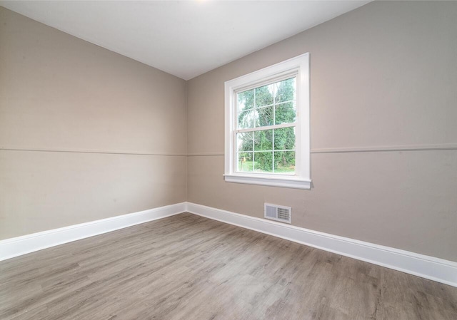 empty room with baseboards, visible vents, and wood finished floors