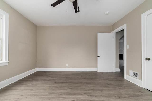 empty room featuring baseboards, visible vents, wood finished floors, and ceiling fan