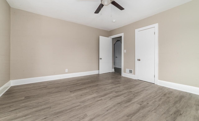 empty room featuring baseboards, ceiling fan, visible vents, and wood finished floors