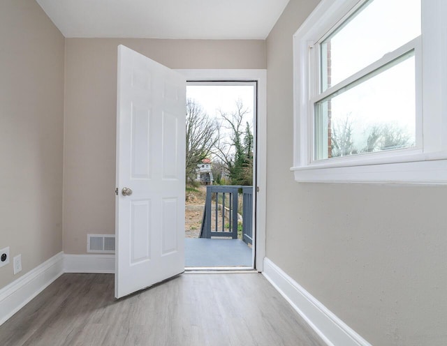 doorway to outside with baseboards, visible vents, and wood finished floors