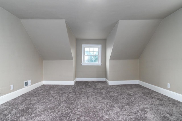 additional living space with baseboards, visible vents, carpet flooring, and vaulted ceiling
