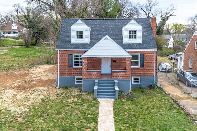 view of front facade with a front lawn, a chimney, a shingled roof, and brick siding