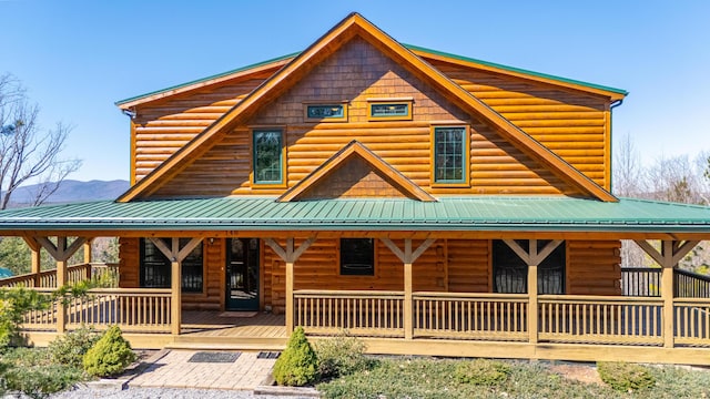 log home with faux log siding, metal roof, and a porch