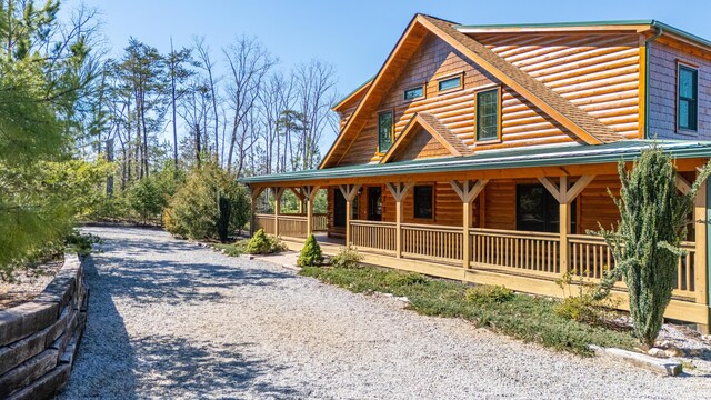 log home featuring covered porch, metal roof, and log veneer siding