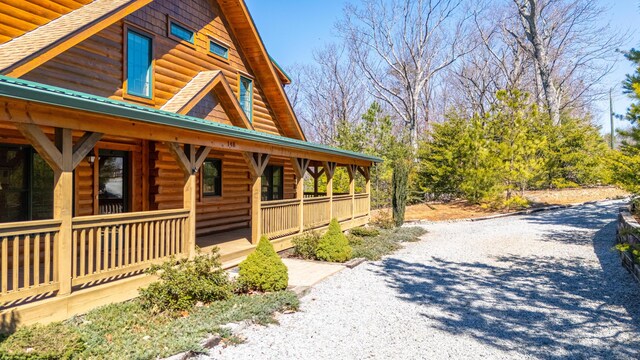 view of home's exterior with faux log siding and a porch