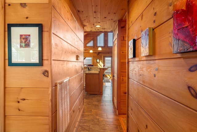 hall featuring visible vents, wood walls, stone finish floor, and wooden ceiling