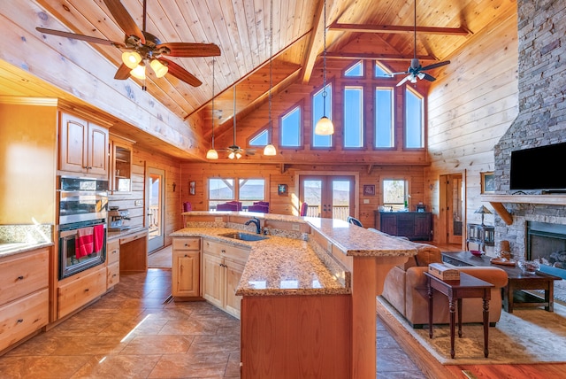 kitchen featuring wood ceiling, stainless steel double oven, a ceiling fan, and open floor plan