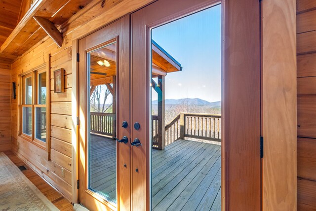 interior space with french doors, wood walls, a mountain view, and hardwood / wood-style floors
