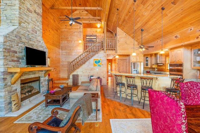 living room with wood walls, ceiling fan, stairway, and wood ceiling
