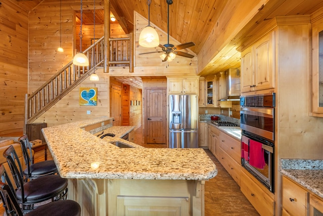 kitchen featuring wooden ceiling, a sink, wood walls, appliances with stainless steel finishes, and light brown cabinets