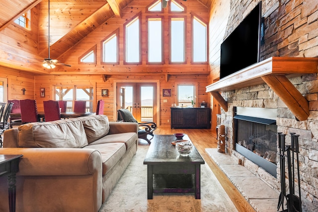 living room featuring light wood-style flooring, wooden walls, a fireplace, lofted ceiling, and wood ceiling