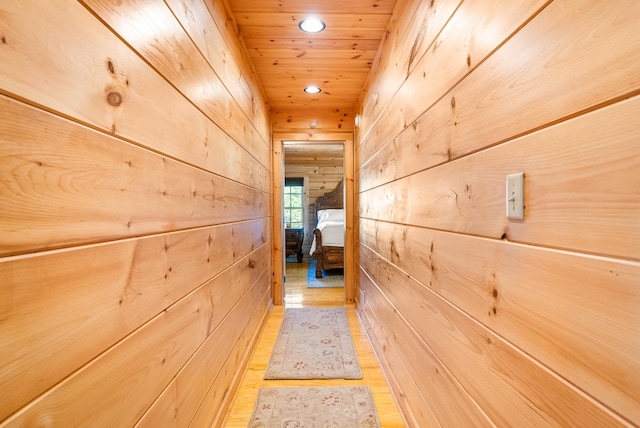 hallway with recessed lighting, light wood-style floors, wood walls, and wood ceiling