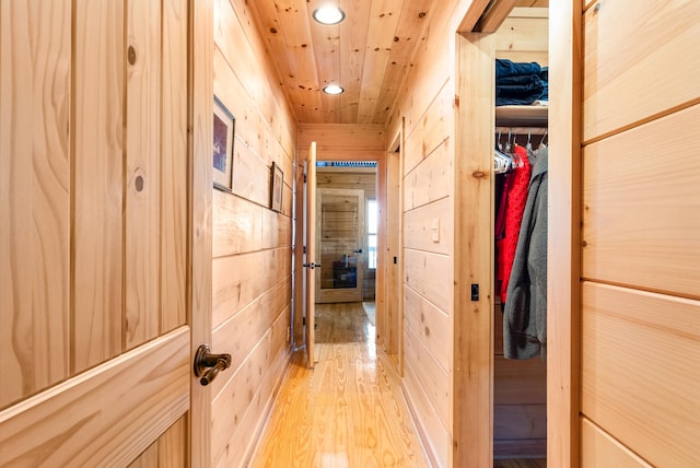 hall featuring light wood-style flooring, wooden ceiling, wood walls, and recessed lighting