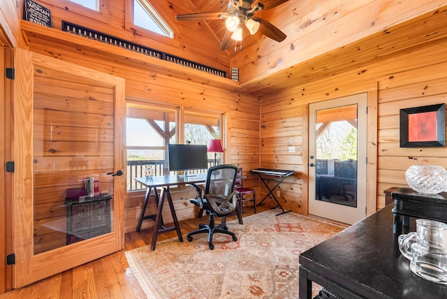 office with a ceiling fan, wood walls, a healthy amount of sunlight, and wood finished floors