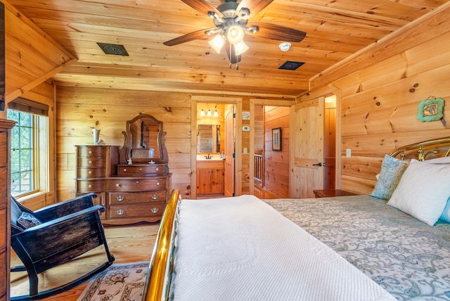 bedroom with connected bathroom, wood walls, wooden ceiling, and wood finished floors