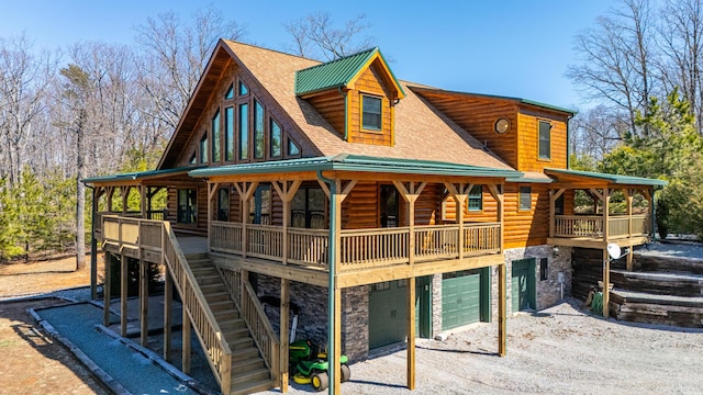 view of front of house with stone siding, driveway, a garage, and roof with shingles