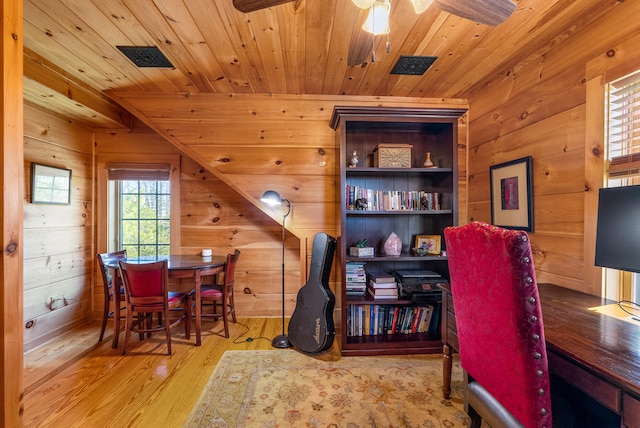 office space featuring wooden ceiling, wooden walls, wood finished floors, visible vents, and ceiling fan