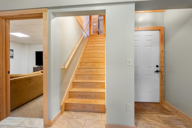 stairway featuring tile patterned floors, baseboards, and a paneled ceiling