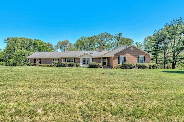 single story home with brick siding, a chimney, and a front lawn
