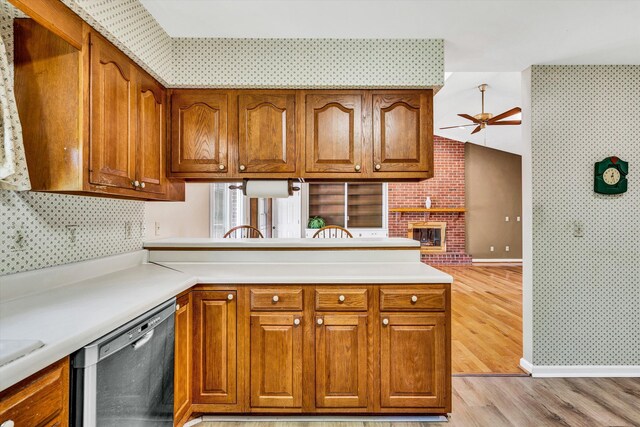 kitchen featuring dishwashing machine, ceiling fan, brown cabinets, and wallpapered walls