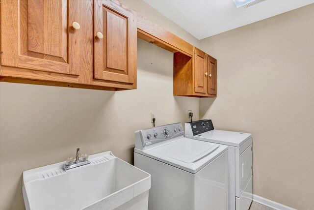 laundry area featuring a sink, baseboards, washing machine and dryer, and cabinet space