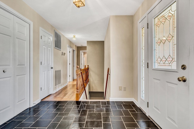 entryway with baseboards, stone finish flooring, and visible vents