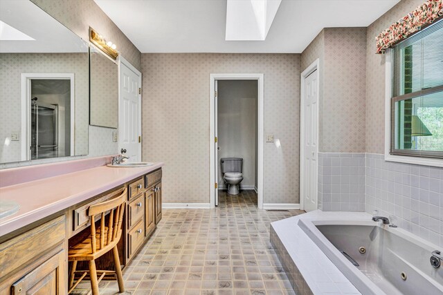 full bathroom featuring a sink, toilet, double vanity, a whirlpool tub, and a skylight