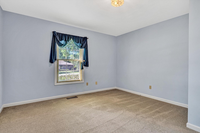 empty room with carpet floors, baseboards, and visible vents