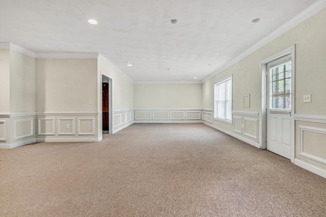 carpeted empty room with a decorative wall, recessed lighting, crown molding, and a wainscoted wall