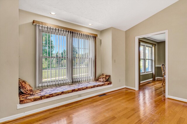 spare room with baseboards, a textured ceiling, wood finished floors, and visible vents