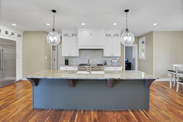 kitchen featuring dark wood-style floors, white cabinetry, light stone countertops, decorative backsplash, and stainless steel built in fridge