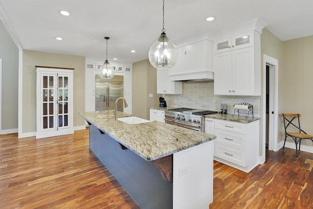 kitchen with custom exhaust hood, high quality appliances, decorative backsplash, and wood finished floors