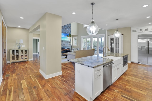 kitchen featuring light wood-type flooring, built in appliances, a sink, and white cabinetry