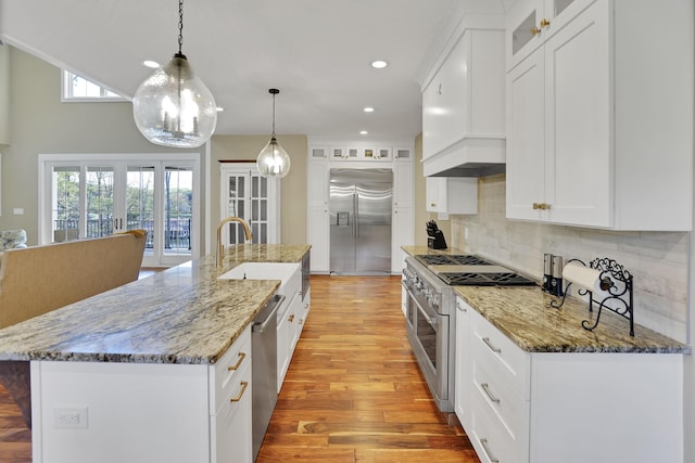 kitchen featuring recessed lighting, glass insert cabinets, backsplash, premium appliances, and light wood finished floors
