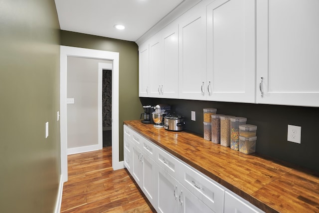 kitchen with butcher block countertops, baseboards, recessed lighting, white cabinetry, and wood finished floors