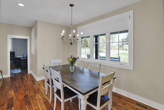 dining area featuring dark wood-type flooring, visible vents, baseboards, and a chandelier